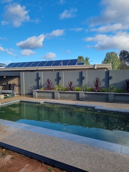 An exposed aggregate pool surround beside a rendered wall and a lap pool