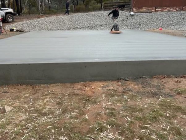 A finished rectangular shed slab on a cleared block with gum trees behind it