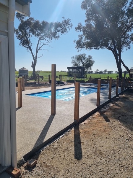 An exposed aggregate pool surround on a rural block with paddocks behind it
