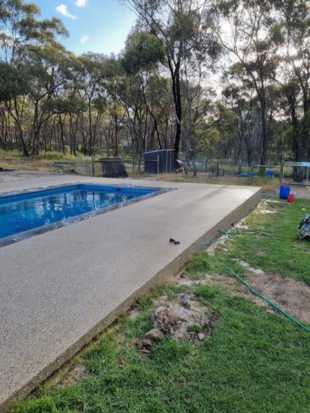 An exposed aggregate pool surround edging a pool on a bush block