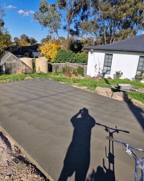 A wide concrete driveway with a swirl finish curving toward a house