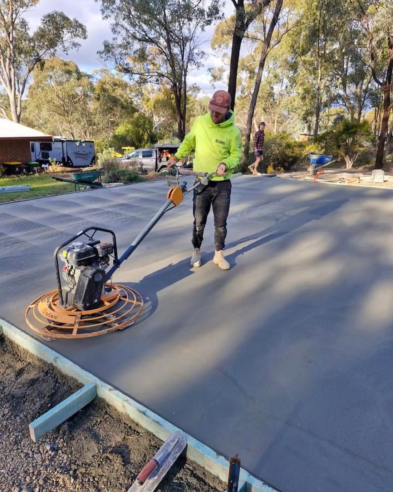 A concreter power-floating a large fresh slab with a ride-behind trowel