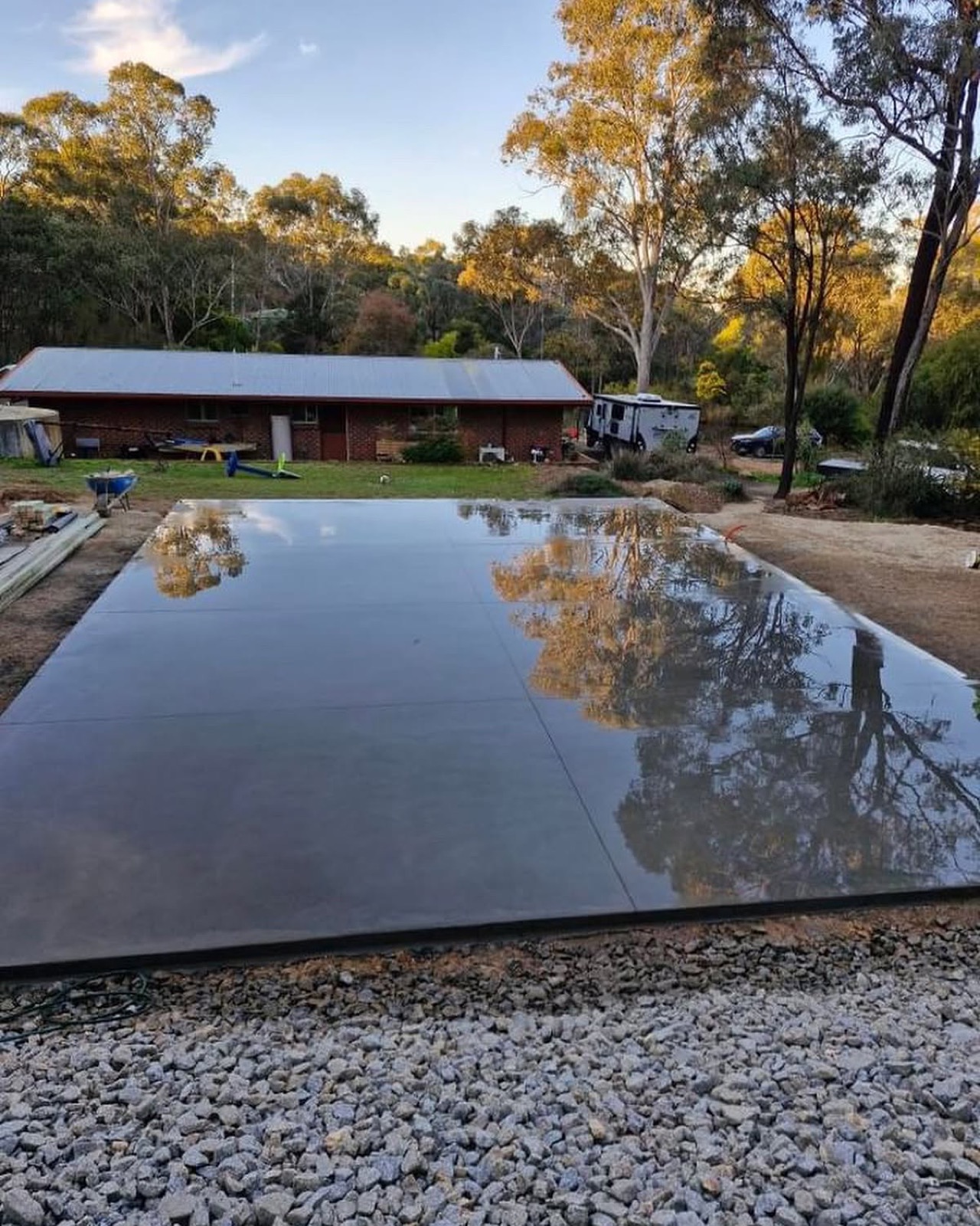 A freshly floated concrete slab holding water on its surface, reflecting the trees above it