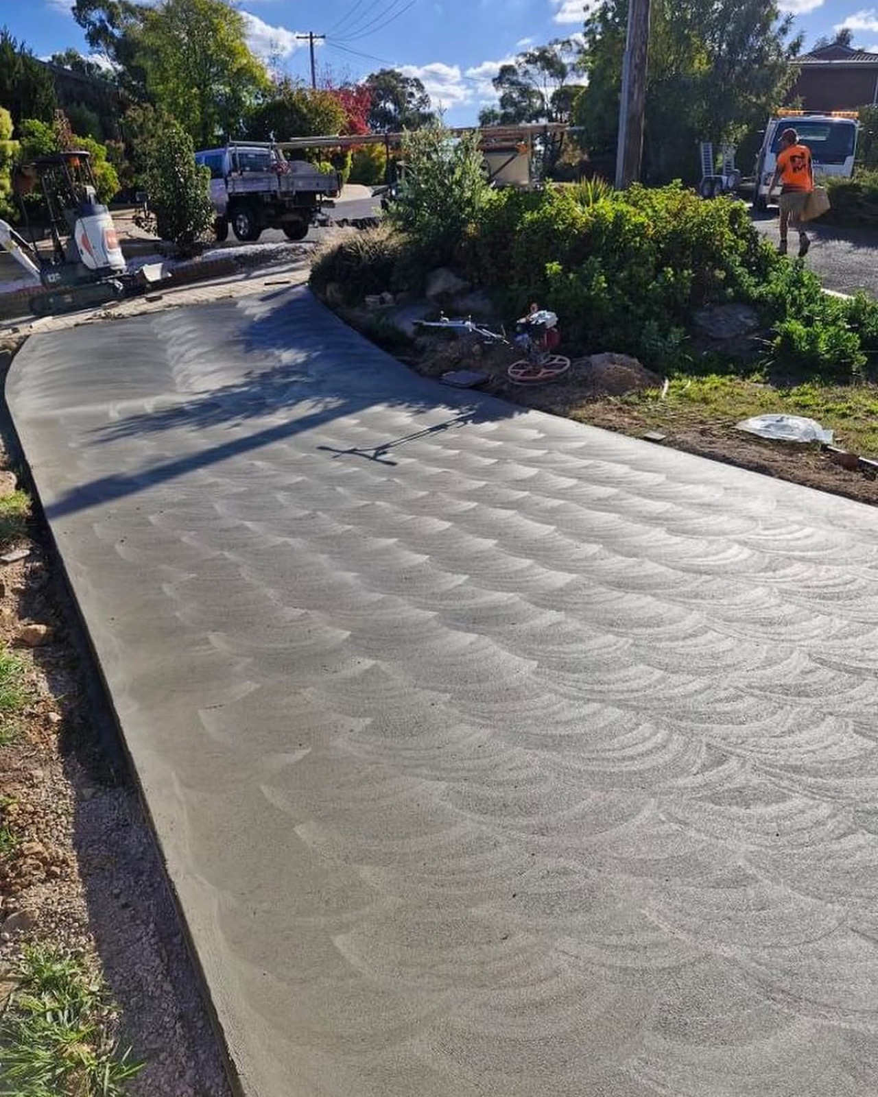 A wide concrete driveway with a swirl finish running up to a house
